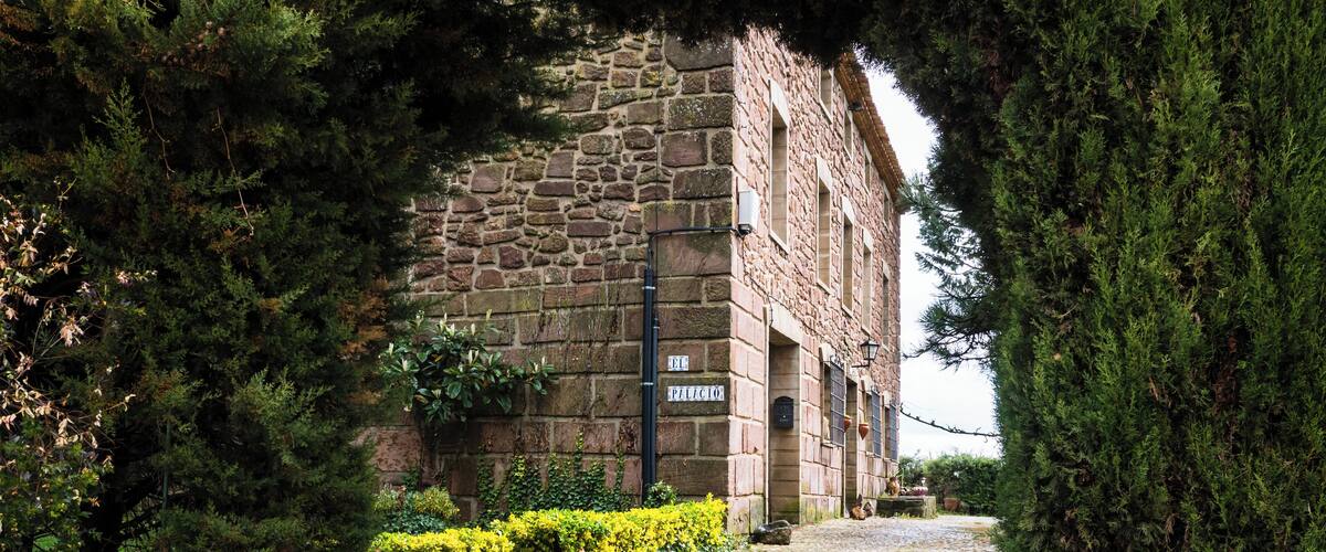 A cobblestone path leading to a stone building with a sign reading "El Pilicio".