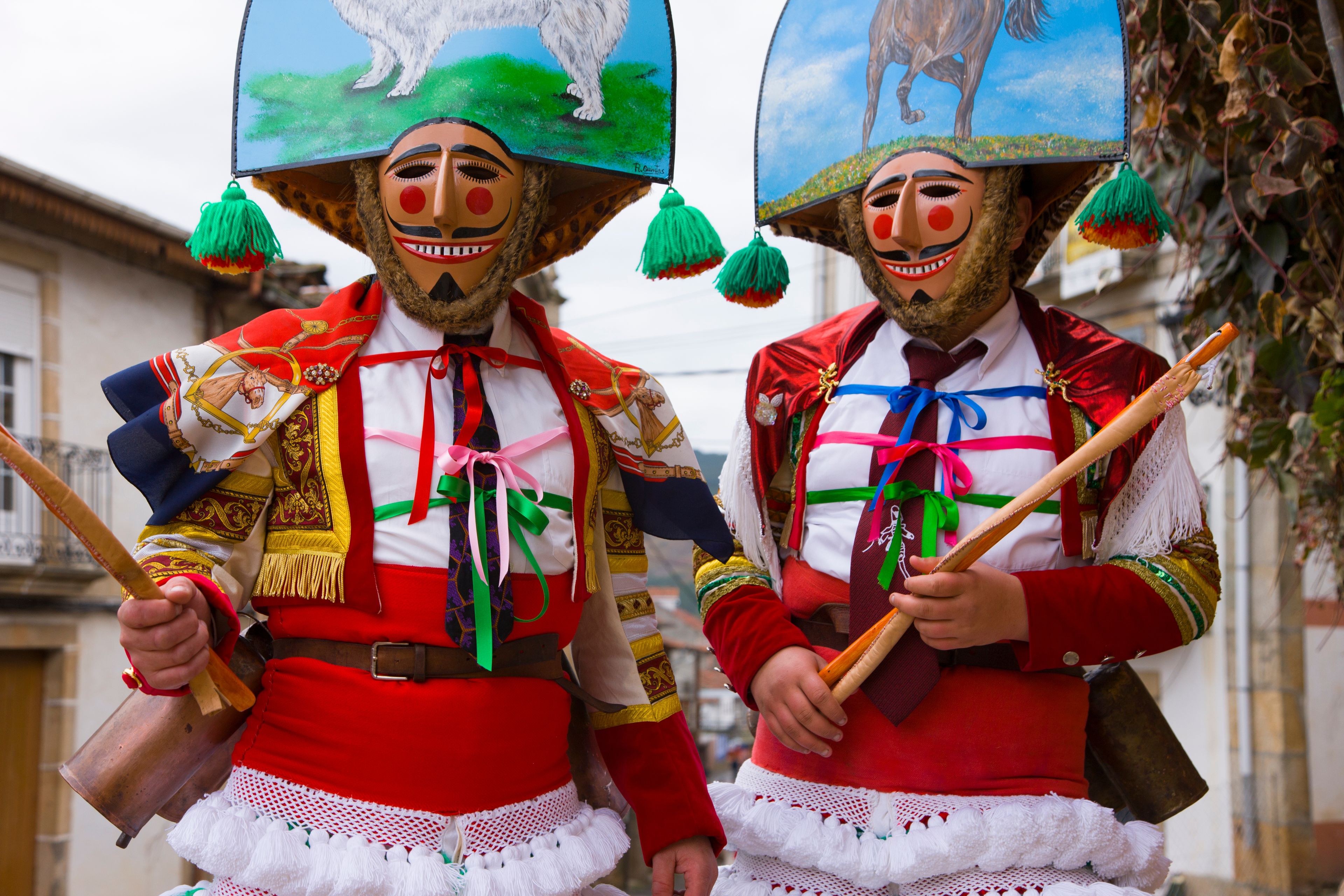 Two individuals in elaborate traditional costumes with large hats, colorful fabrics, and accessories.
