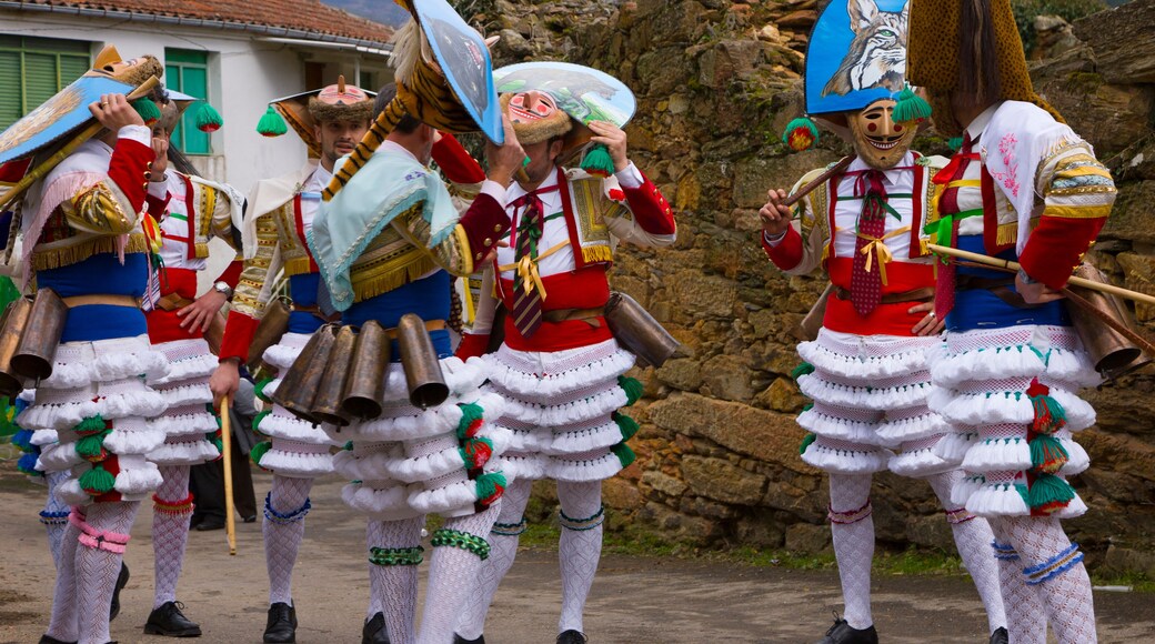 A group of people in traditional costumes with white skirts, colorful patterns, and headpieces.
