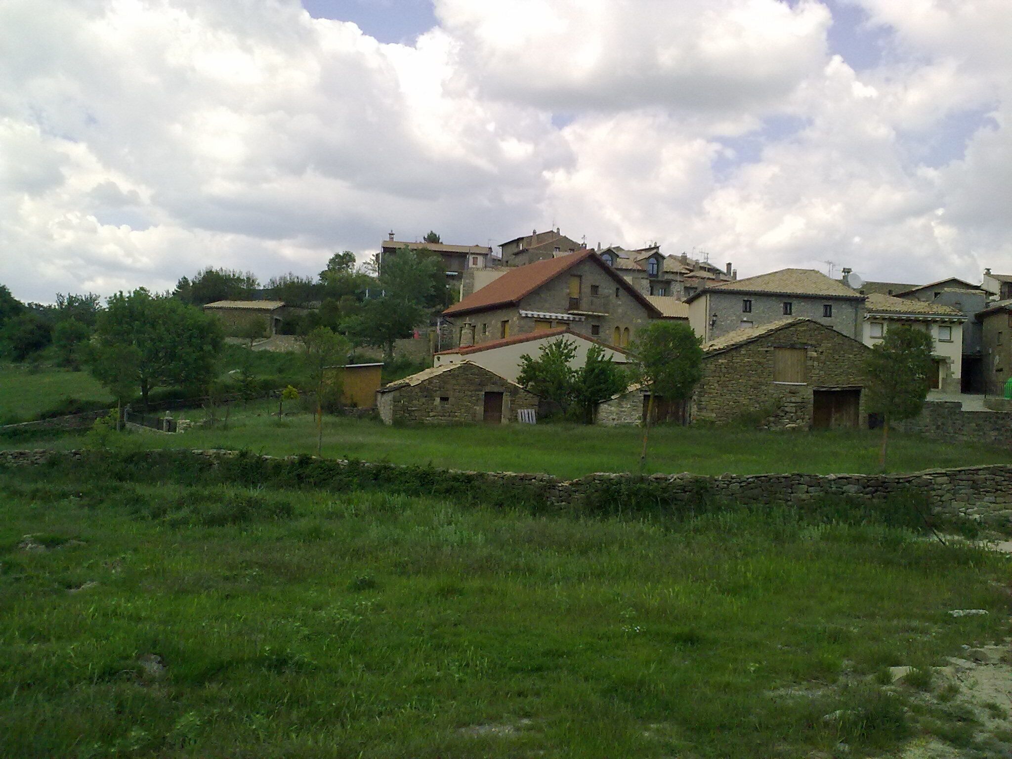 A rural village with stone houses and a stone wall.