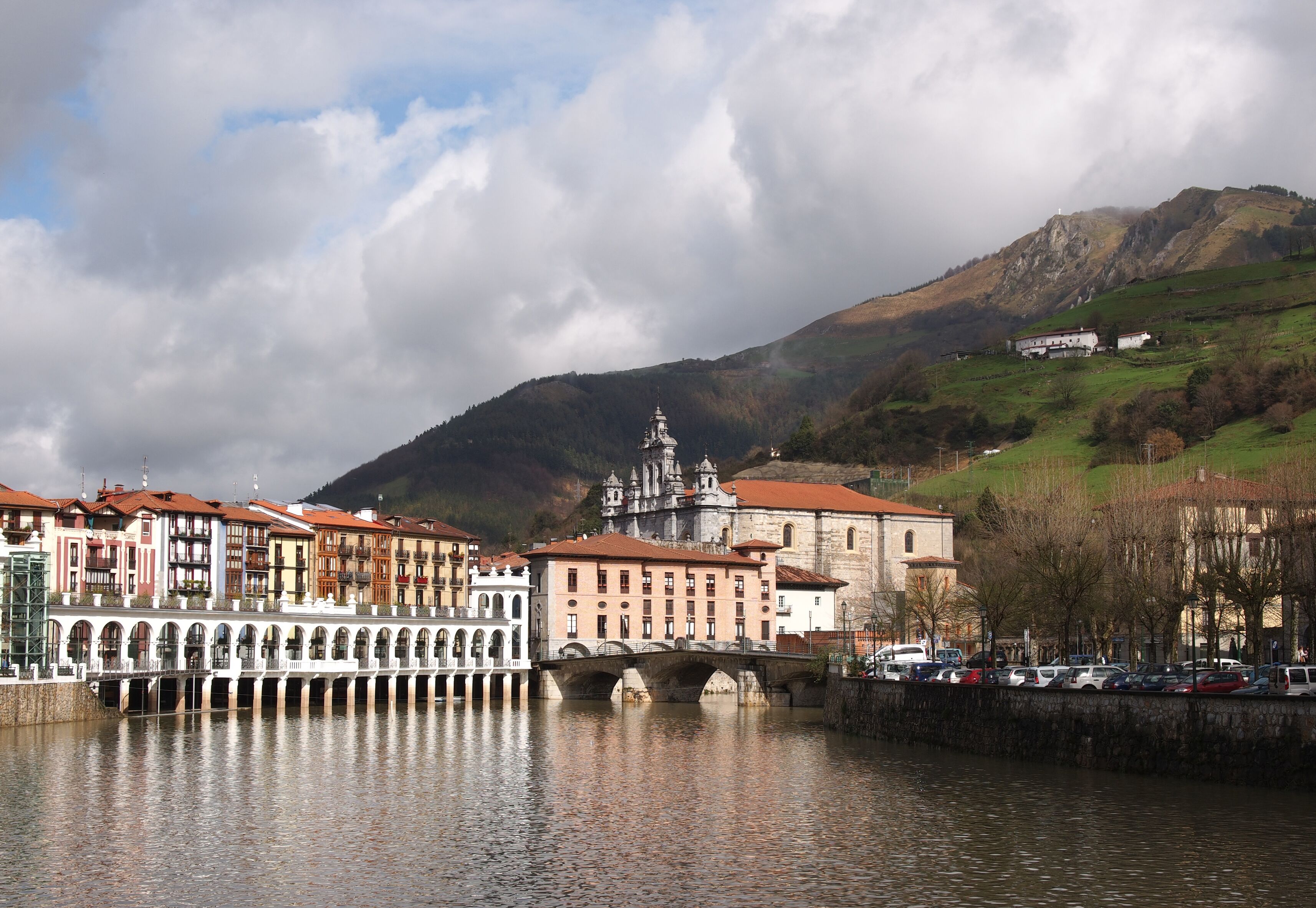 A river with a bridge, historic buildings, and a mountain in the background.