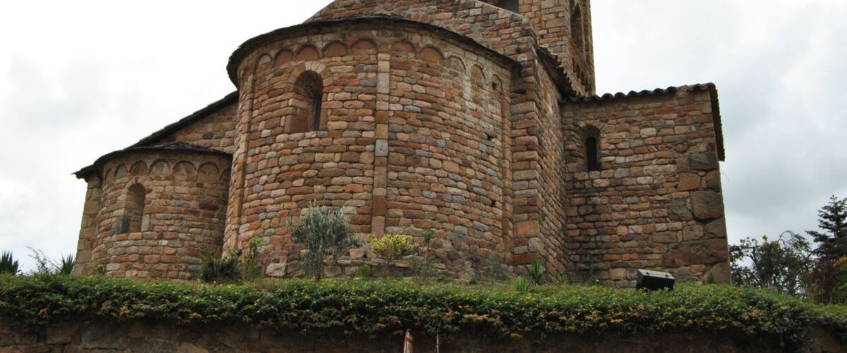 A historic stone church with a bell tower and arched windows.