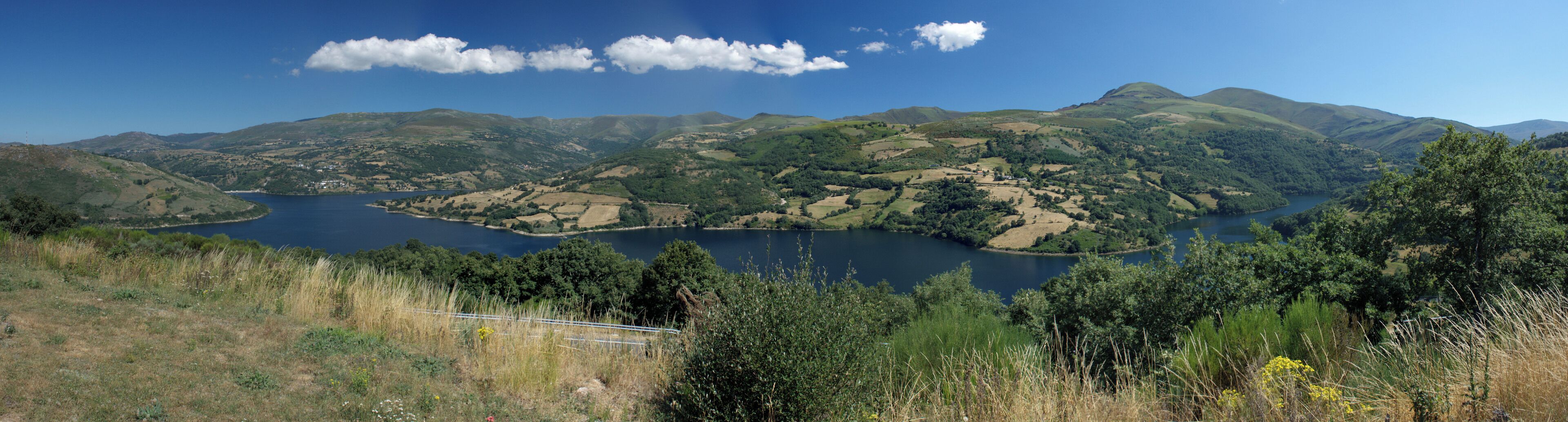 A lake surrounded by rolling hills and dense forests.
