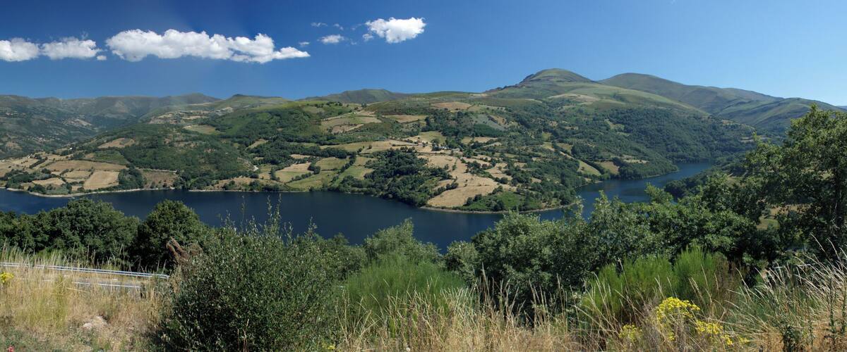 A lake surrounded by rolling hills and dense forests.