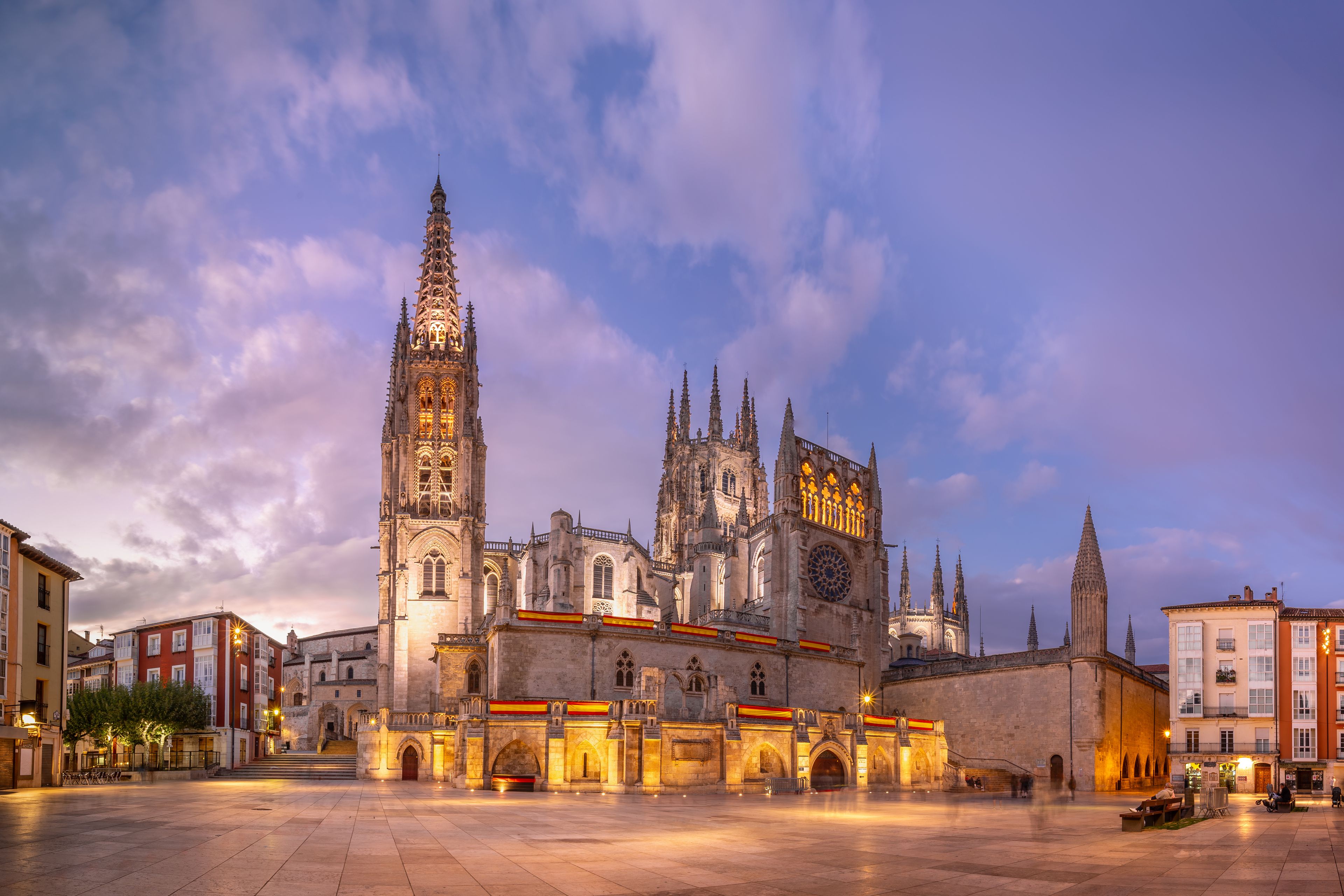 Uma catedral histórica com arquitetura detalhada e uma torre imponente, ao pôr do sol.