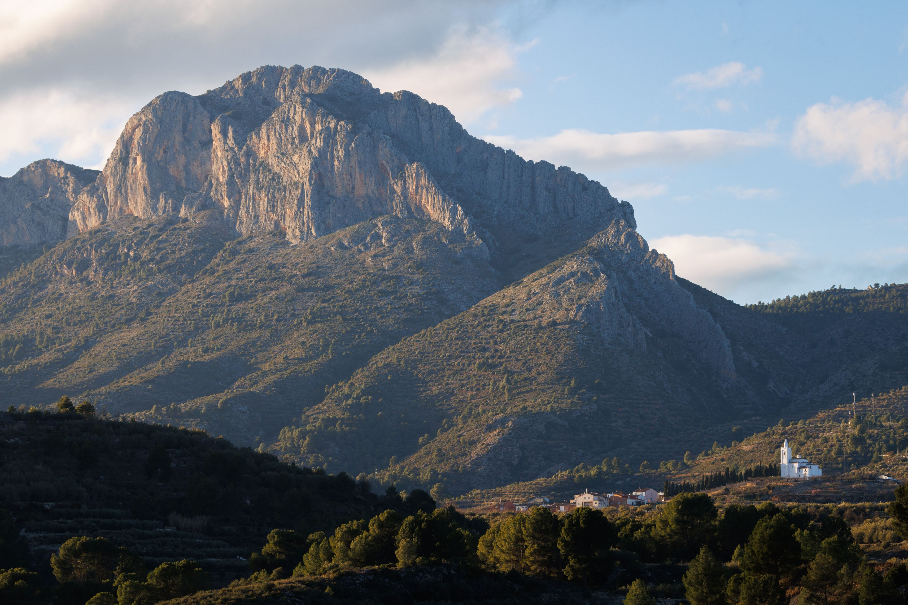 A rugged mountain with a church at its base.