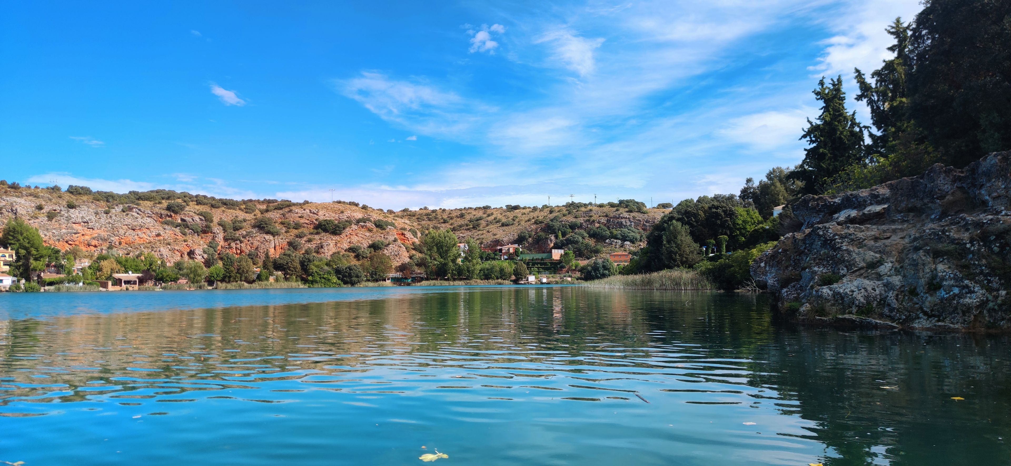 Un lago tranquilo con aguas azul cristalino, rodeado de colinas rocosas y vegetación escasa.