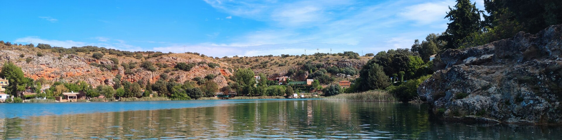 Un lago tranquilo con aguas azul cristalino, rodeado de colinas rocosas y vegetación escasa.