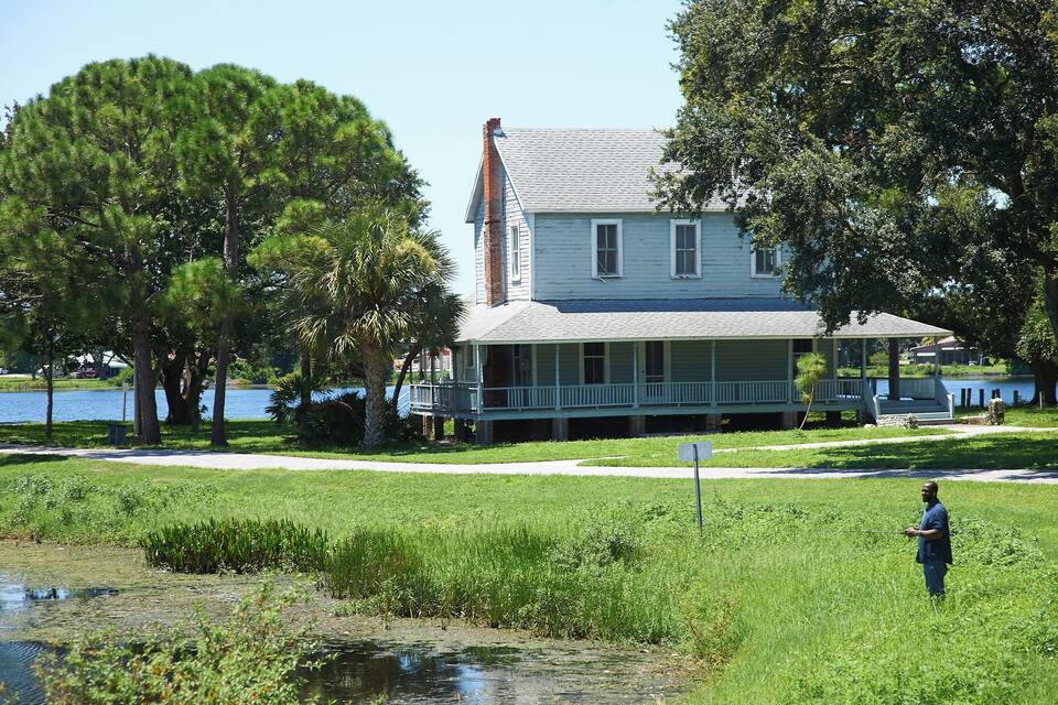 A house by a lake with a grassy area in front.