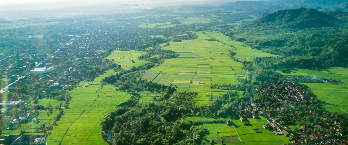 A green valley with fields, a village, and a mountain in the background.