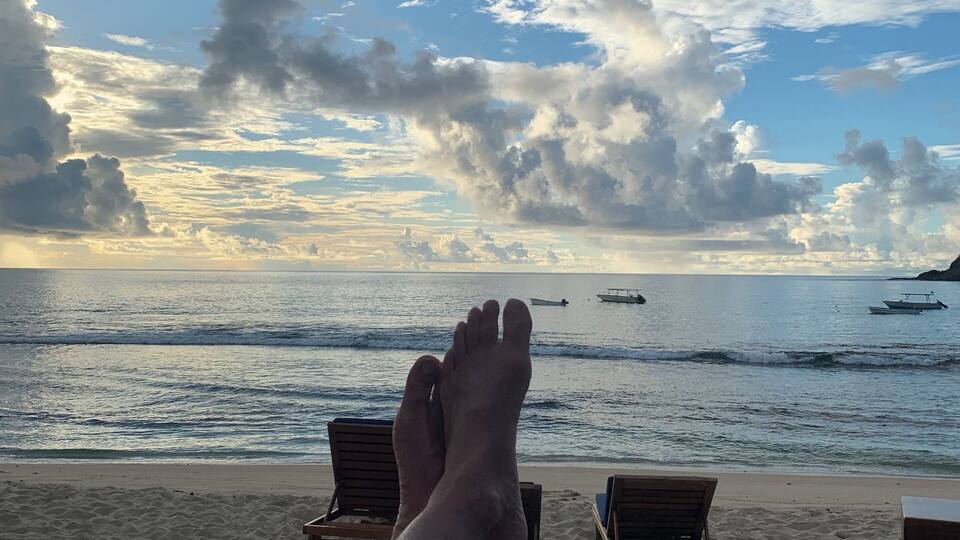 A beach with lounge chairs and a view of the ocean.