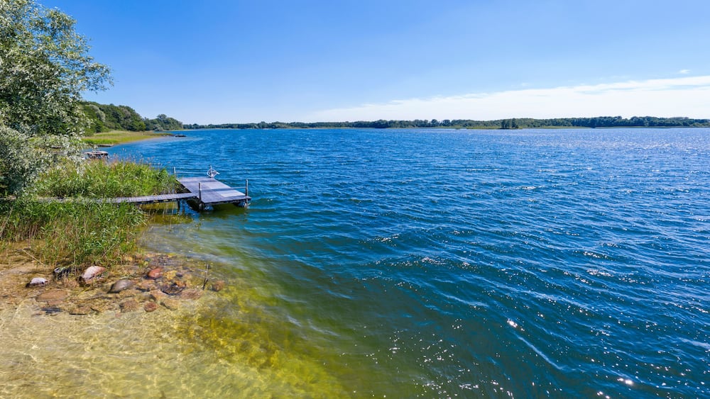 Summer panoramic lakeview with clear blue sky and water, sunbatch platform at Karsko Wielkie lake, picture taken from a shallow lakeshore, Poland