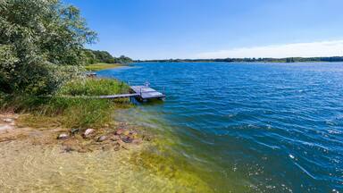 Summer panoramic lakeview with clear blue sky and water, sunbatch platform at Karsko Wielkie lake, picture taken from a shallow lakeshore, Poland
