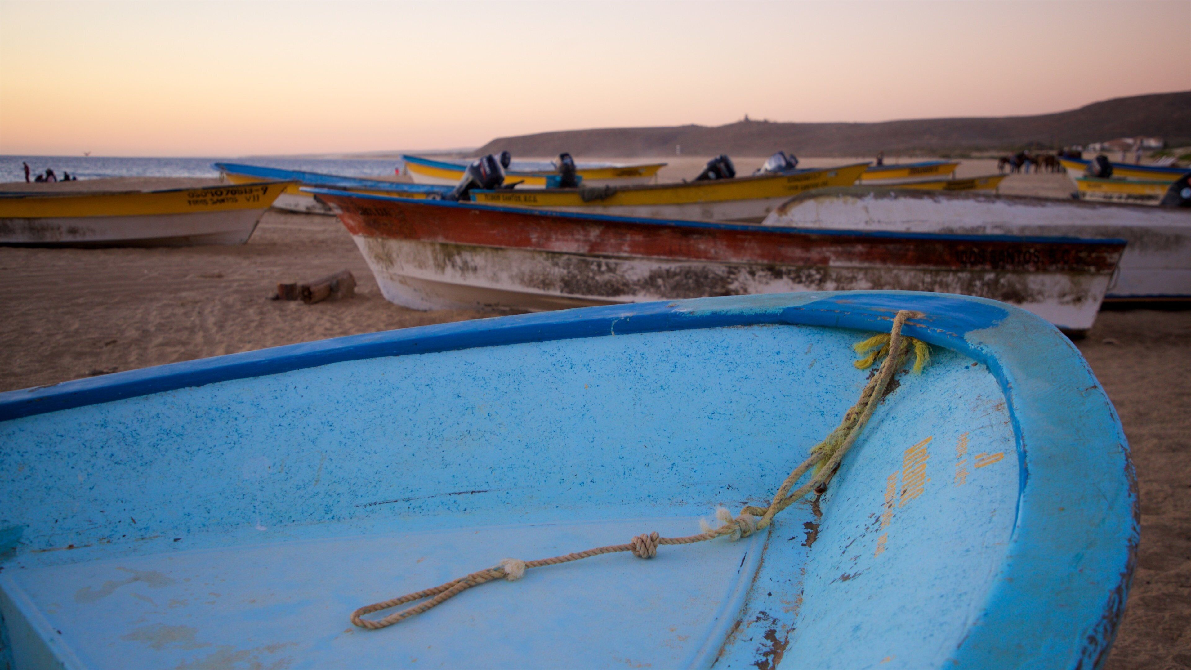 A row of boats on a beach with a sunset in the background.