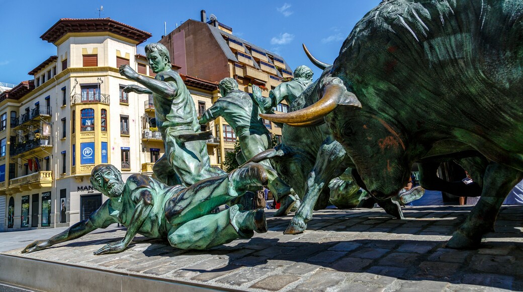 A bronze bull statue with a bullfight scene, including a bull and two men.