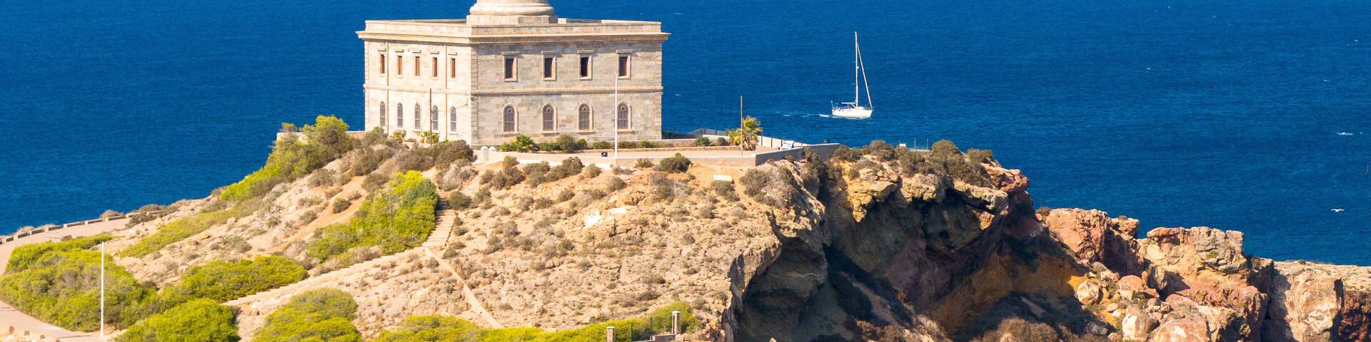 A tall lighthouse on a rocky cliff with the ocean in the background.