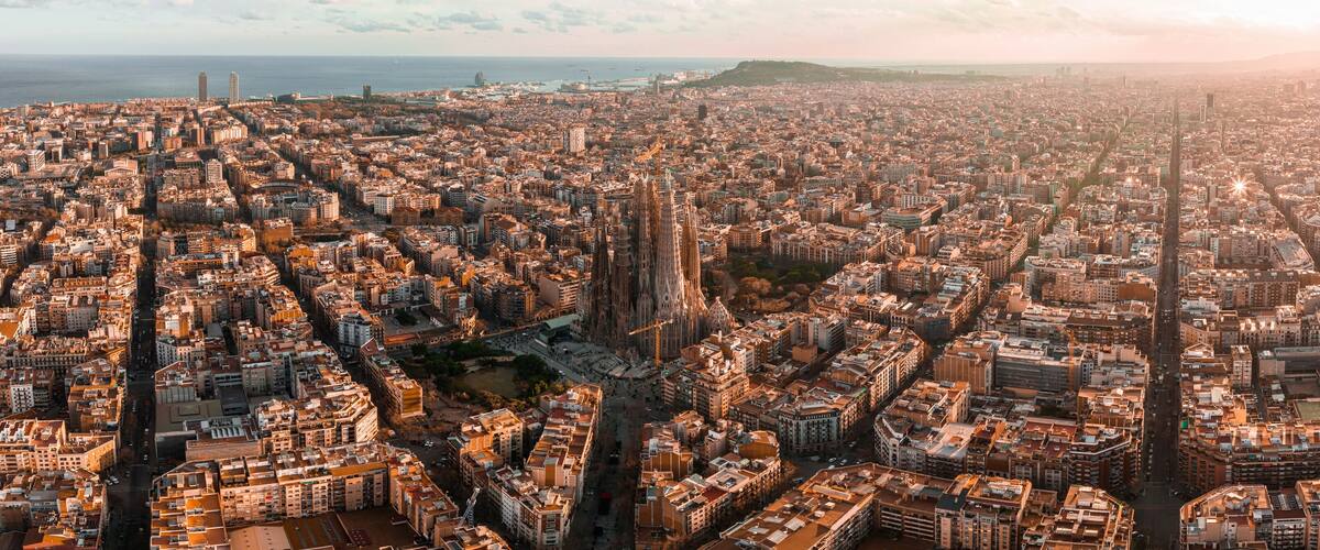 Aerial view of Barcelona City Skyline and Sagrada Familia Cathedral at sunset. Eixample residential famous urban grid. Cityscape with typical urban octagon blocks