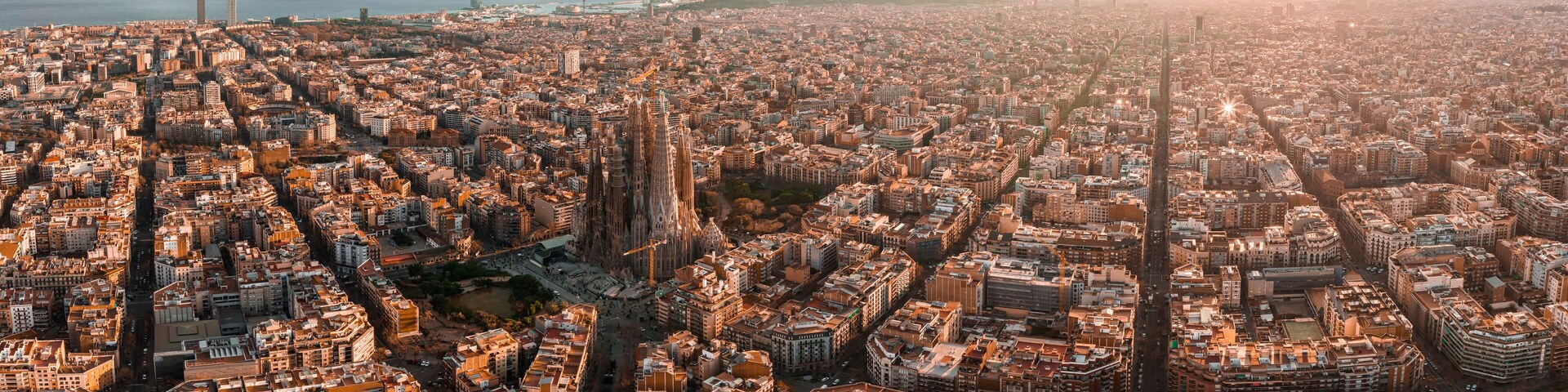 Aerial view of Barcelona City Skyline and Sagrada Familia Cathedral at sunset. Eixample residential famous urban grid. Cityscape with typical urban octagon blocks
