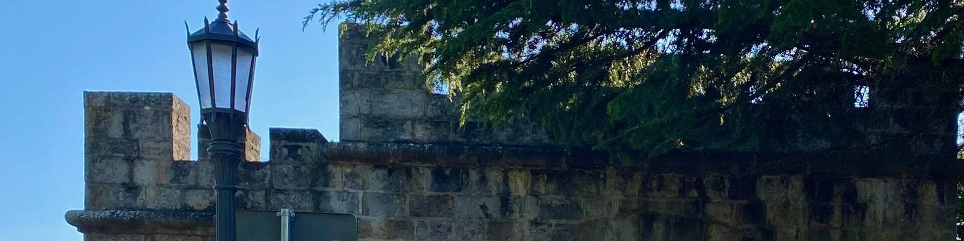 A stone archway with a street lamp and a trash can in the foreground.