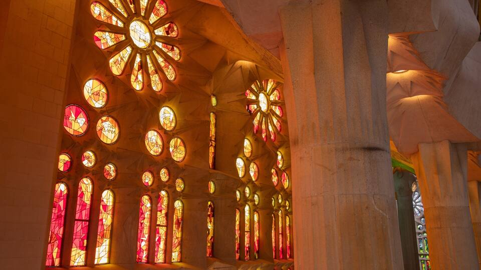 En kyrkinteriör med färgglada målade glasfönster och pelare av sten.
