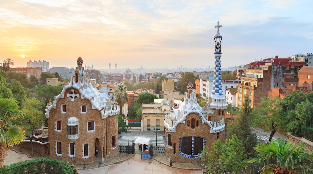 A view of a cityscape with a distinctive building featuring a tower with a cross on top, surrounded by lush greenery and other buildings.