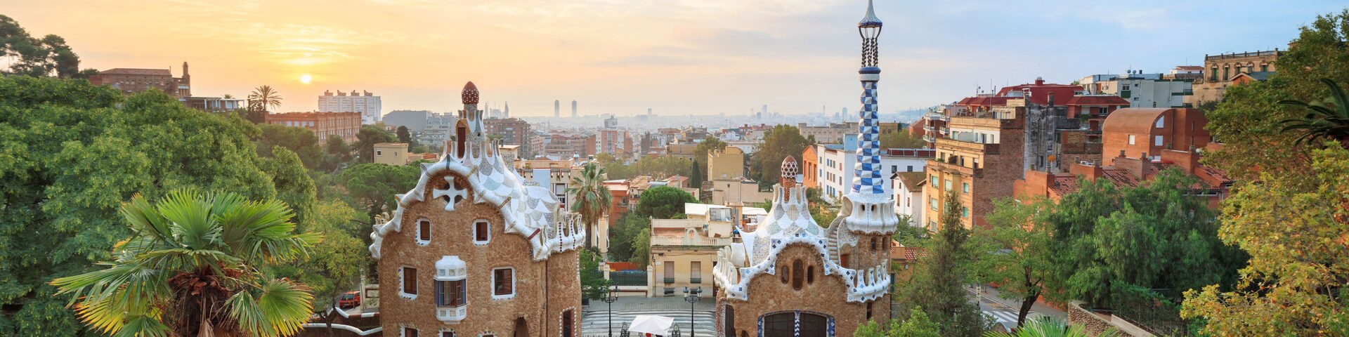 Une vue sur un paysage urbain, avec un bâtiment remarquable surmonté d’une tour coiffée d’une croix, le tout entouré d’une végétation luxuriante et d’autres bâtiments.