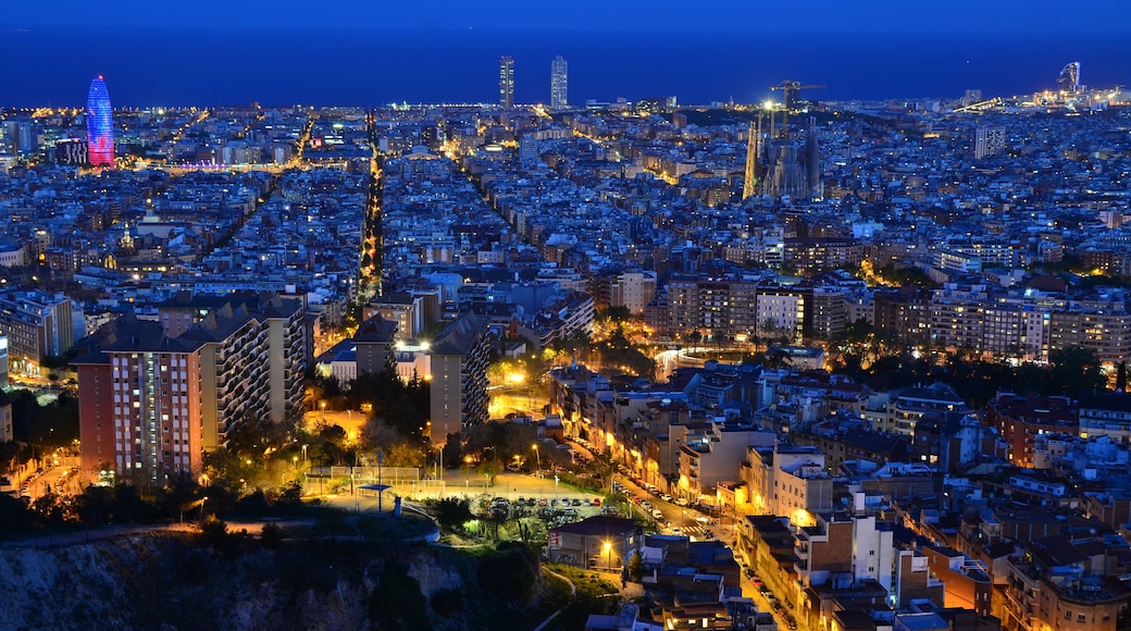 A cityscape at dusk with illuminated buildings and a prominent tower.
