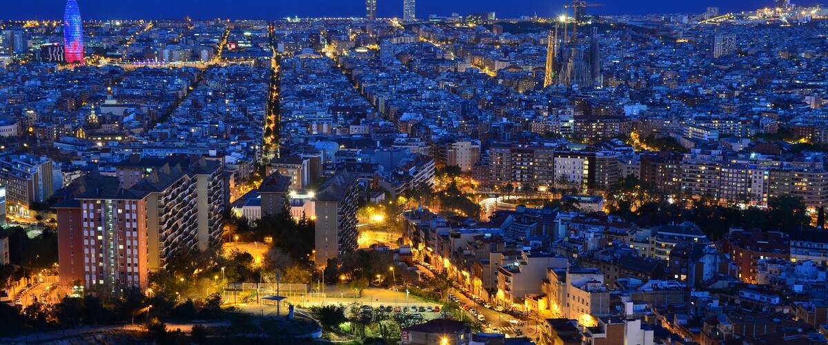 Une vue sur une ville au crépuscule, avec des bâtiments illuminés et une tour imposante.