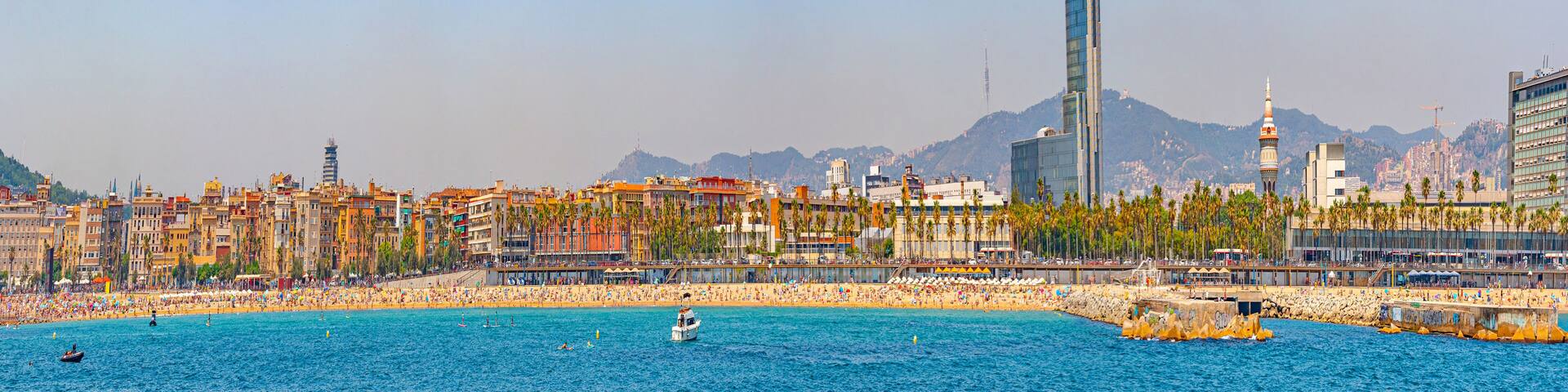 A coastal cityscape with a beach, palm trees, and a prominent tower.