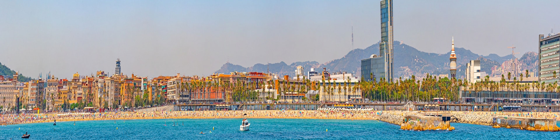 Un paysage urbain côtier avec une plage, des palmiers et une tour imposante.