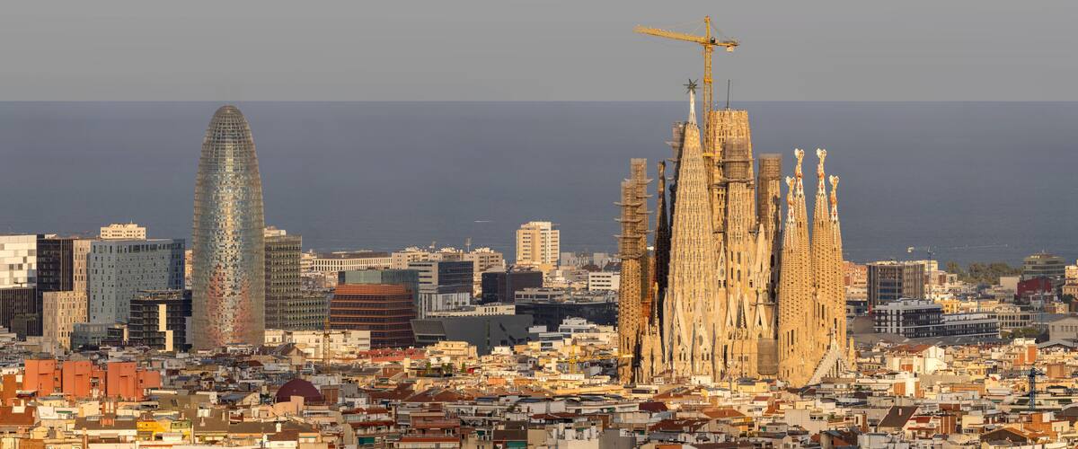 Tele view on Torre Glòries and Sagrada Familia in Barcelona, Spain, from Parque del Turó del Puxtet in golden hour