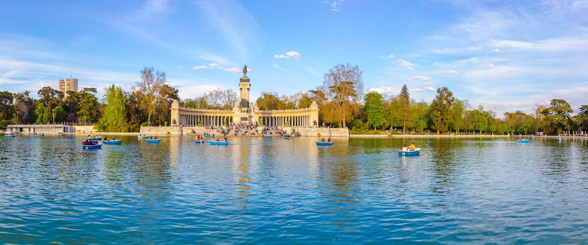 A park with a central monument, a lake, and boats.