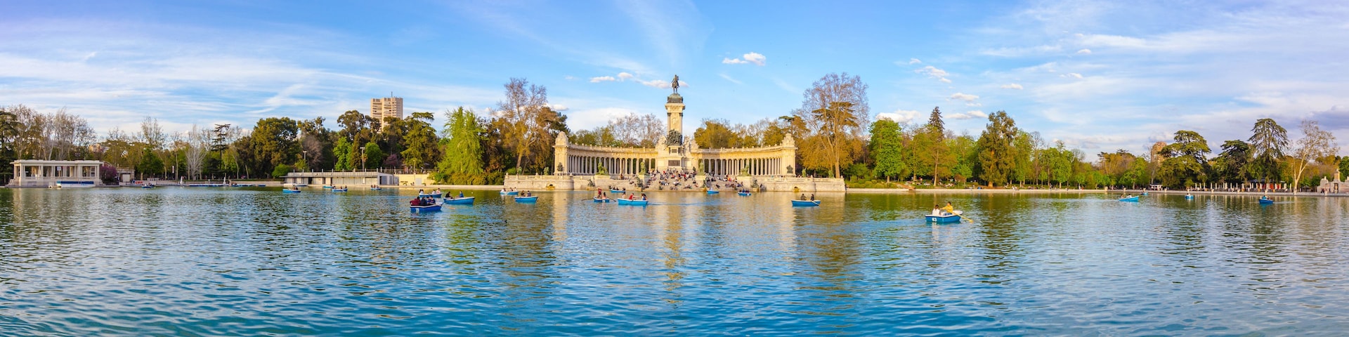 Ein Park mit einem zentralen Denkmal, einem See und Booten.