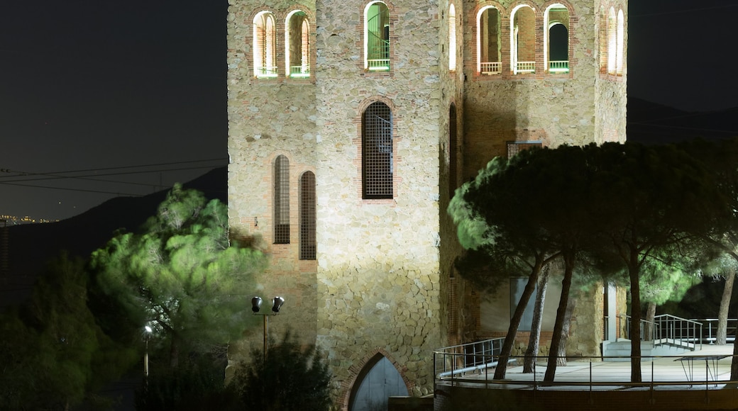 Una torre de piedra histórica con ventanas de arco y un balcón, iluminada por la noche.