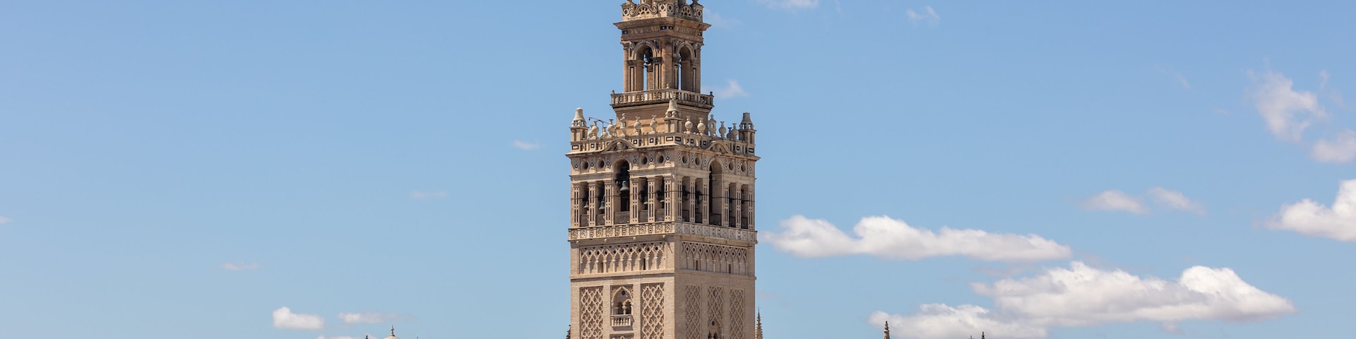 Uma torre histórica com detalhes arquitetônicos elaborados, rodeada por um horizonte urbano.