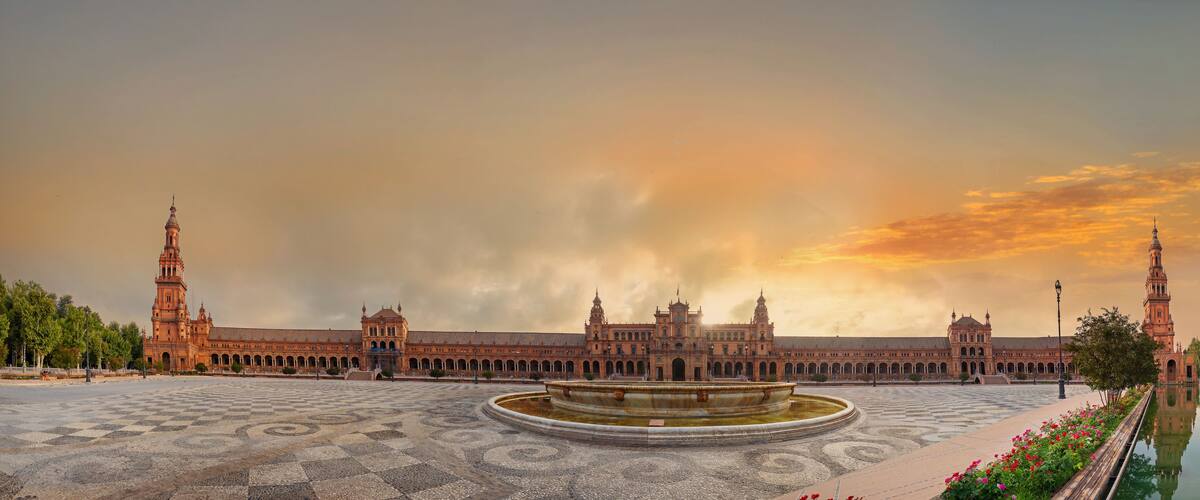 Un edificio histórico imponente con múltiples torres y un patio central con una fuente.