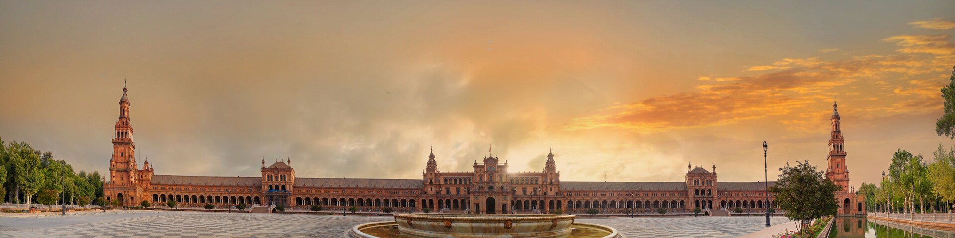 Um imponente edifício histórico com várias torres e um pátio central com uma fonte.