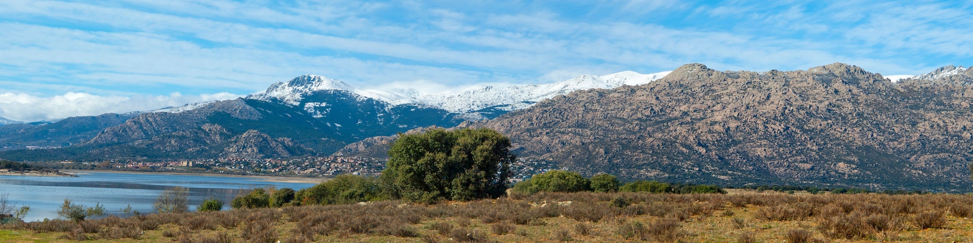 Paisagem montanhosa com um lago e uma cidade no vale.