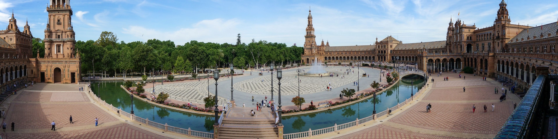 Uma grande praça aberta com uma fonte central, rodeada por edifícios históricos com cúpulas e torres.