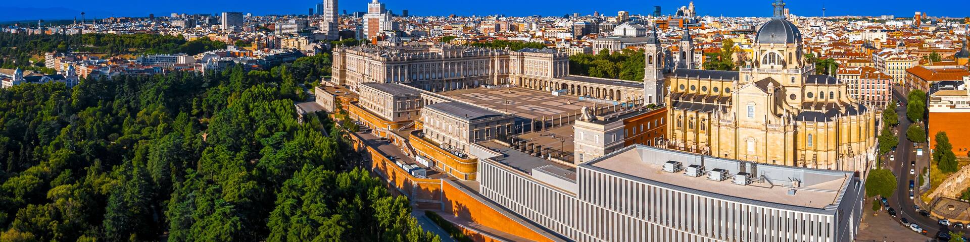 A cityscape with a prominent historical building complex, dense urban area, and a clear blue sky.