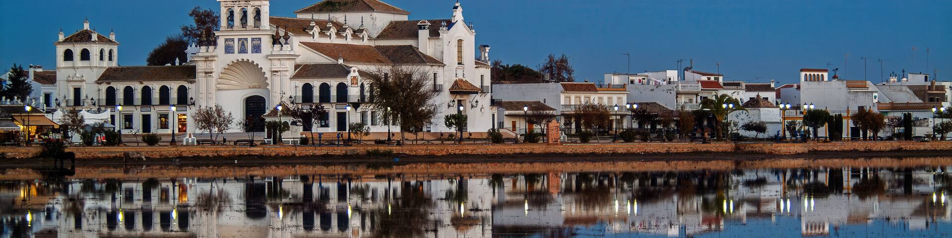 A historic church with a bell tower and a reflection in the water.