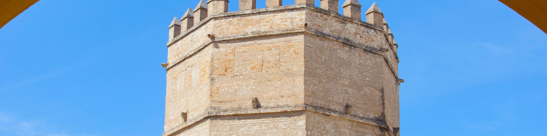 Una torre histórica con almenas, bajo un cielo azul despejado.