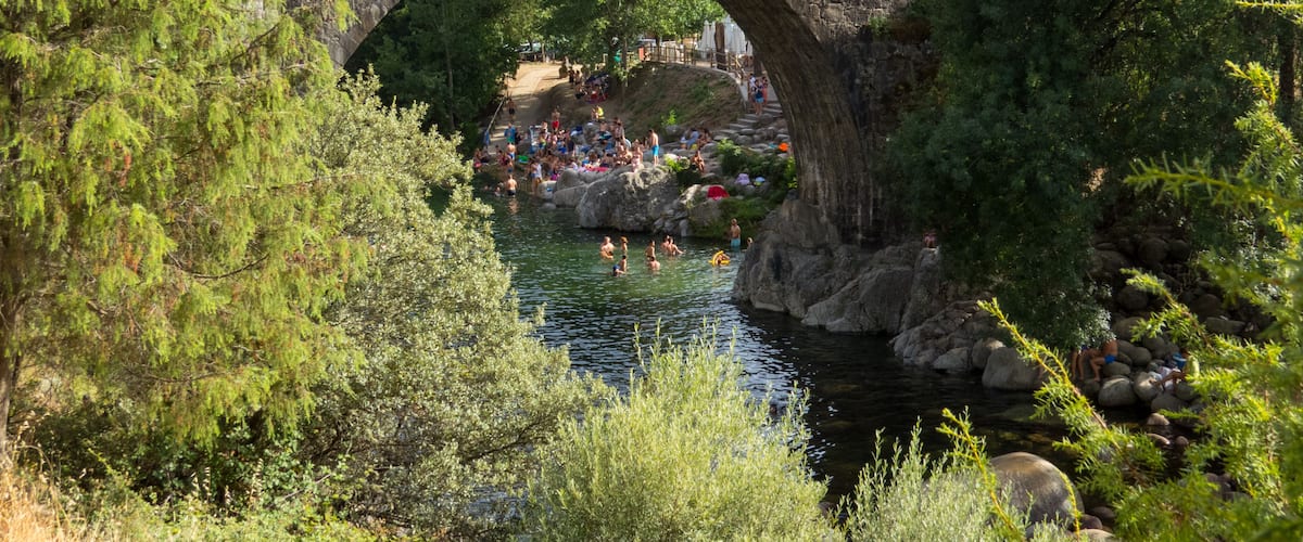 Un puente de piedra sobre un río, rodeado de árboles y rocas.