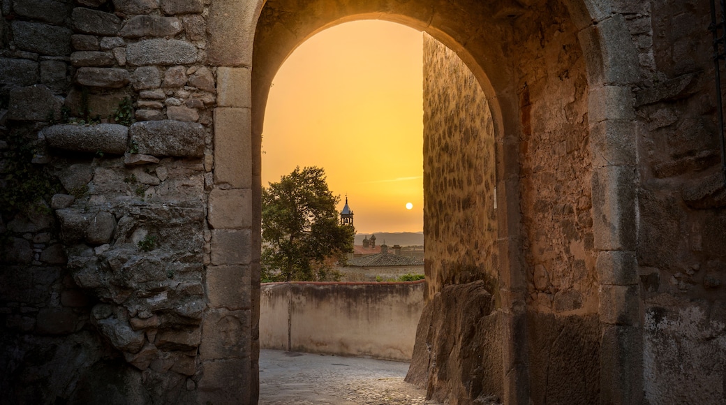 An ancient stone archway with a sunset in the background.