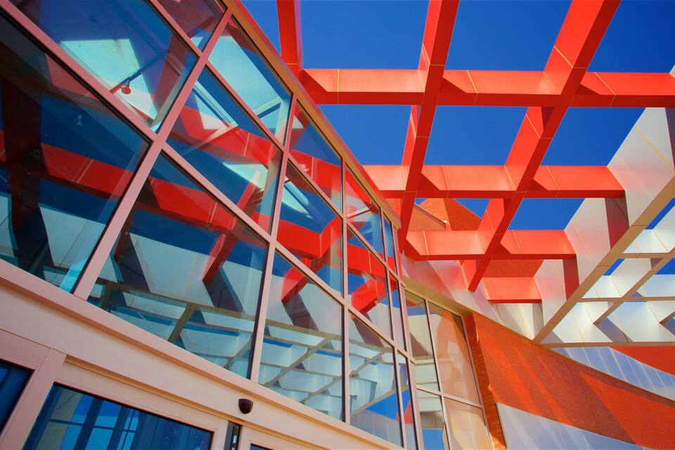 A modern building with a glass facade and geometric red and white structural elements.