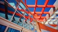 Een modern gebouw met een glazen gevel en geometrische rode en witte structurele elementen.