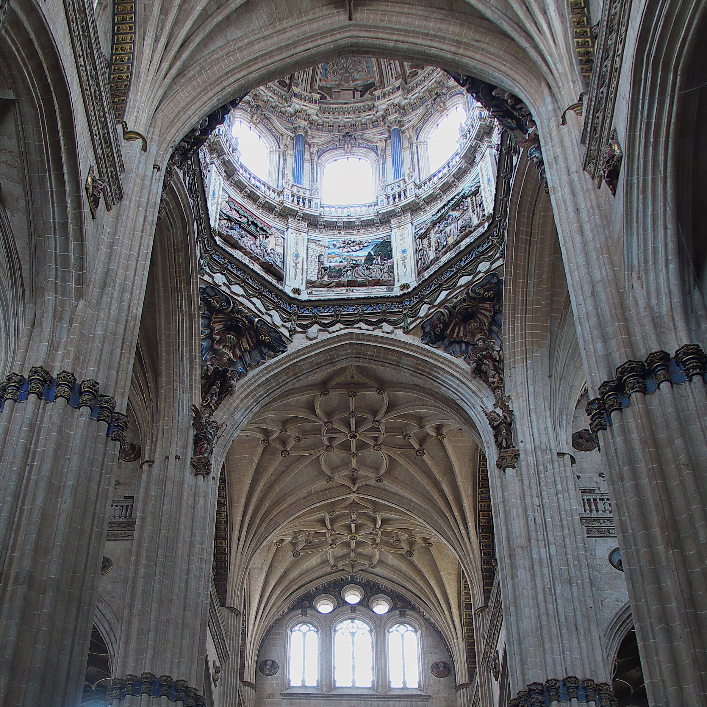 Interior de una catedral con techos abovedados altos, intrincadas esculturas de piedra y una cúpula central.