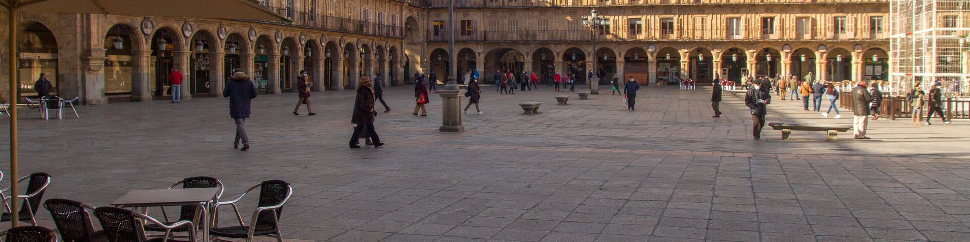 A spacious courtyard with a large, ornate building featuring multiple arches and columns.