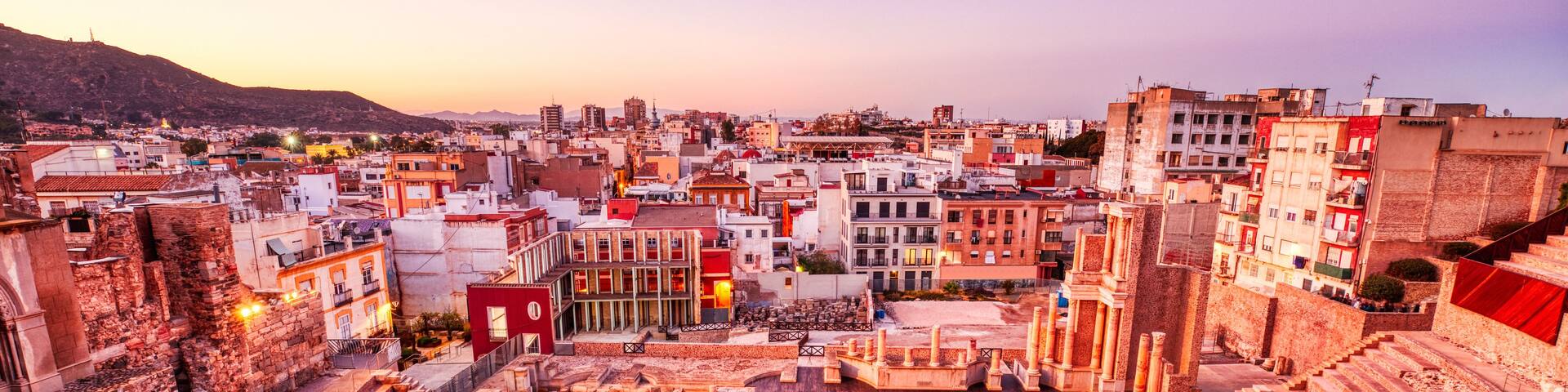 An ancient amphitheater surrounded by a cityscape with modern buildings.