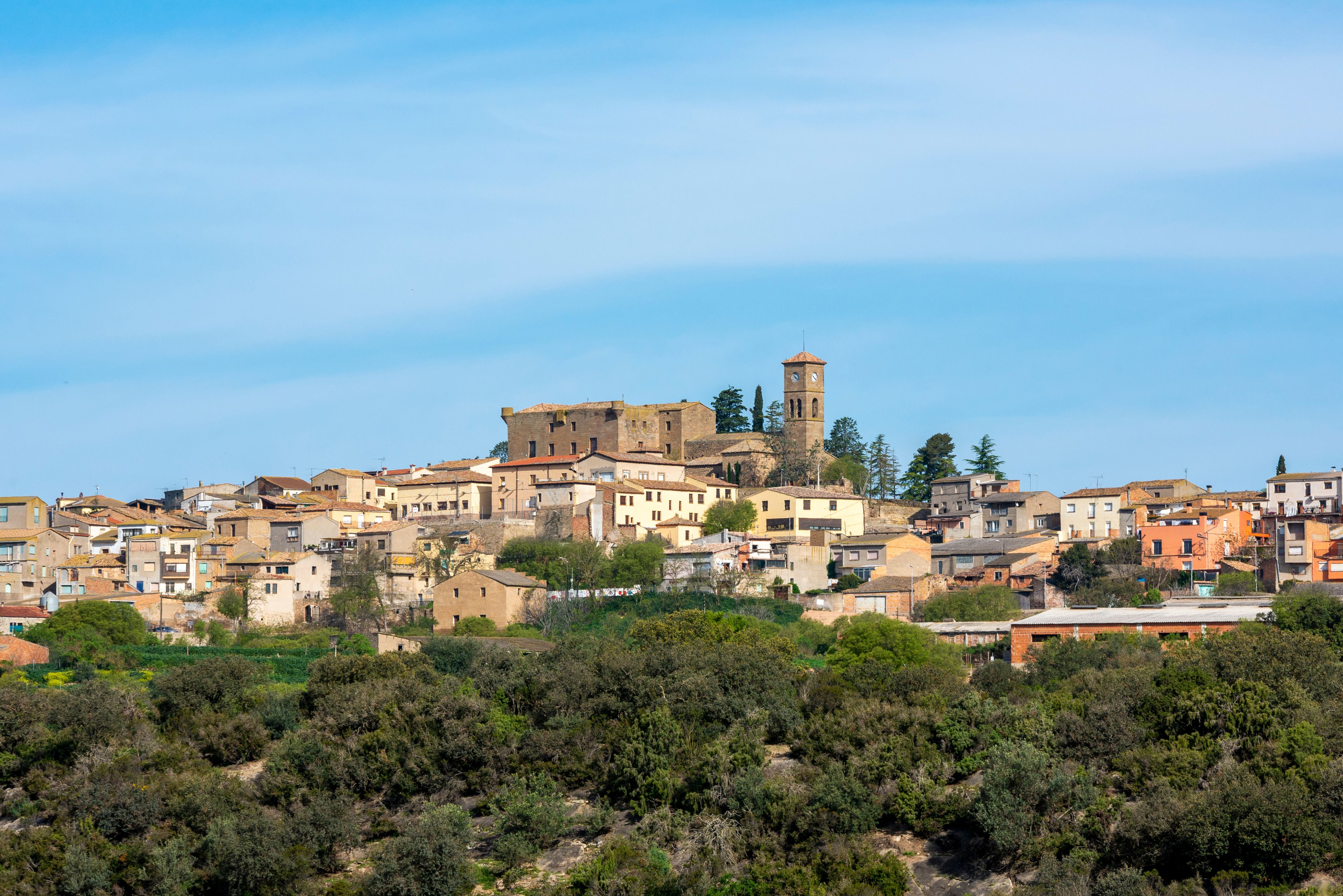 Un poble històric amb una torre destacada i edificis densos, de terrasses.